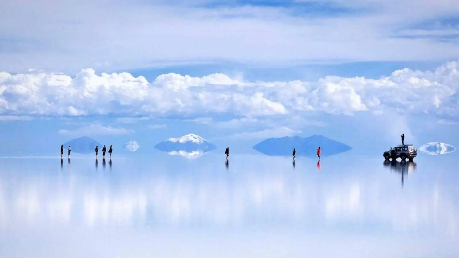 A vehicle crossing a vast flat white salt plain under a wide sky