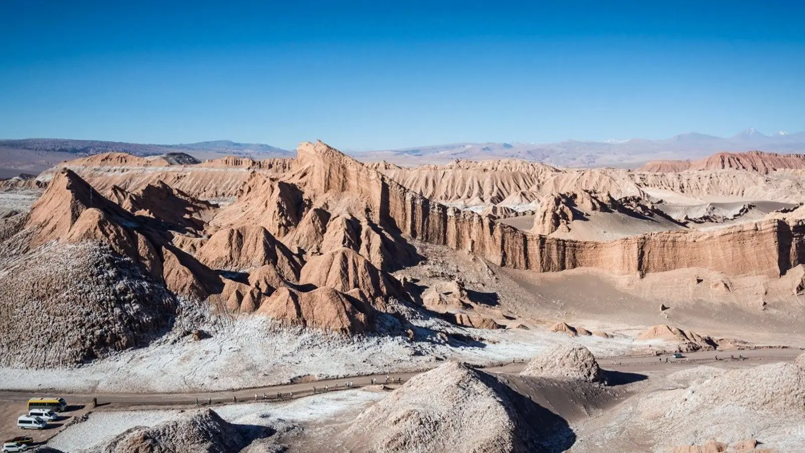 Visitors on a ridge above an eroded salt valley in late afternoon light